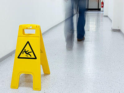 Ein gelbes Warnschild für Rutschgefahr steht in einem Flur.